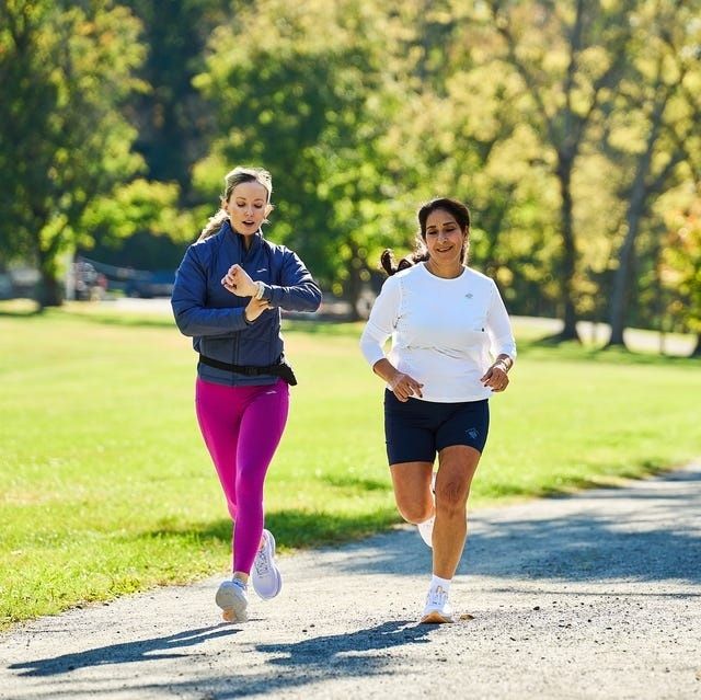 Zwei Frauen laufen gemeinsam auf einem Parkweg und halten ihr Tempo